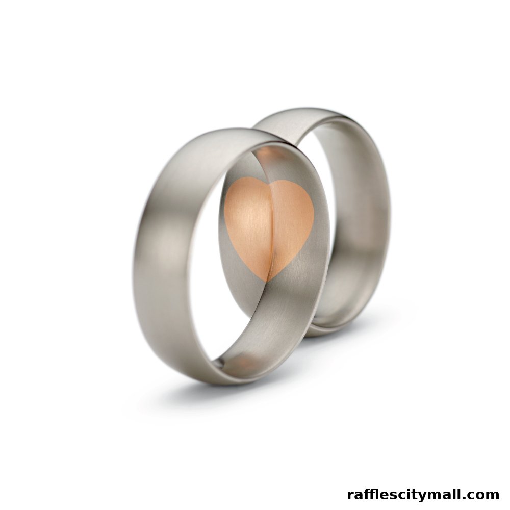 Two silver wedding rings with a rose gold heart inlay on a white background.