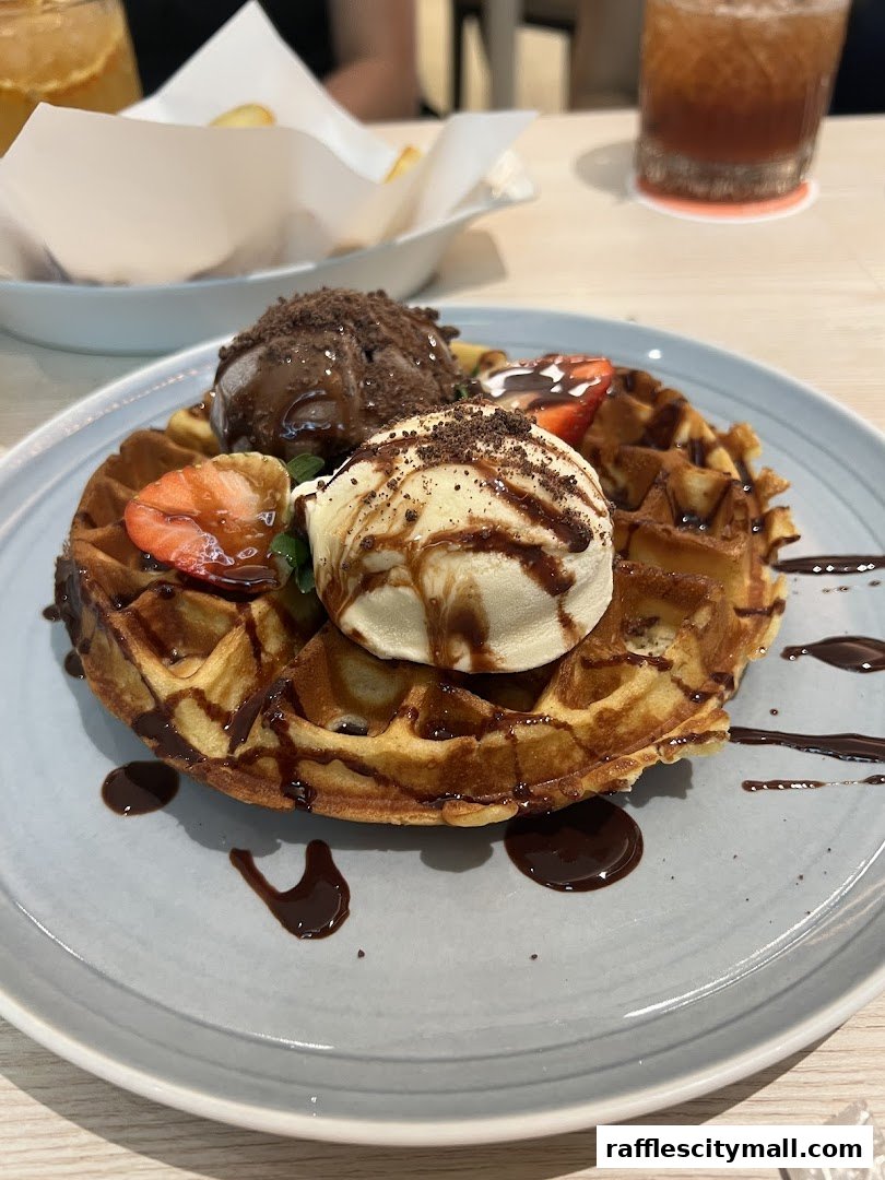 A delicious waffle topped with ice cream, chocolate sauce, and strawberries.