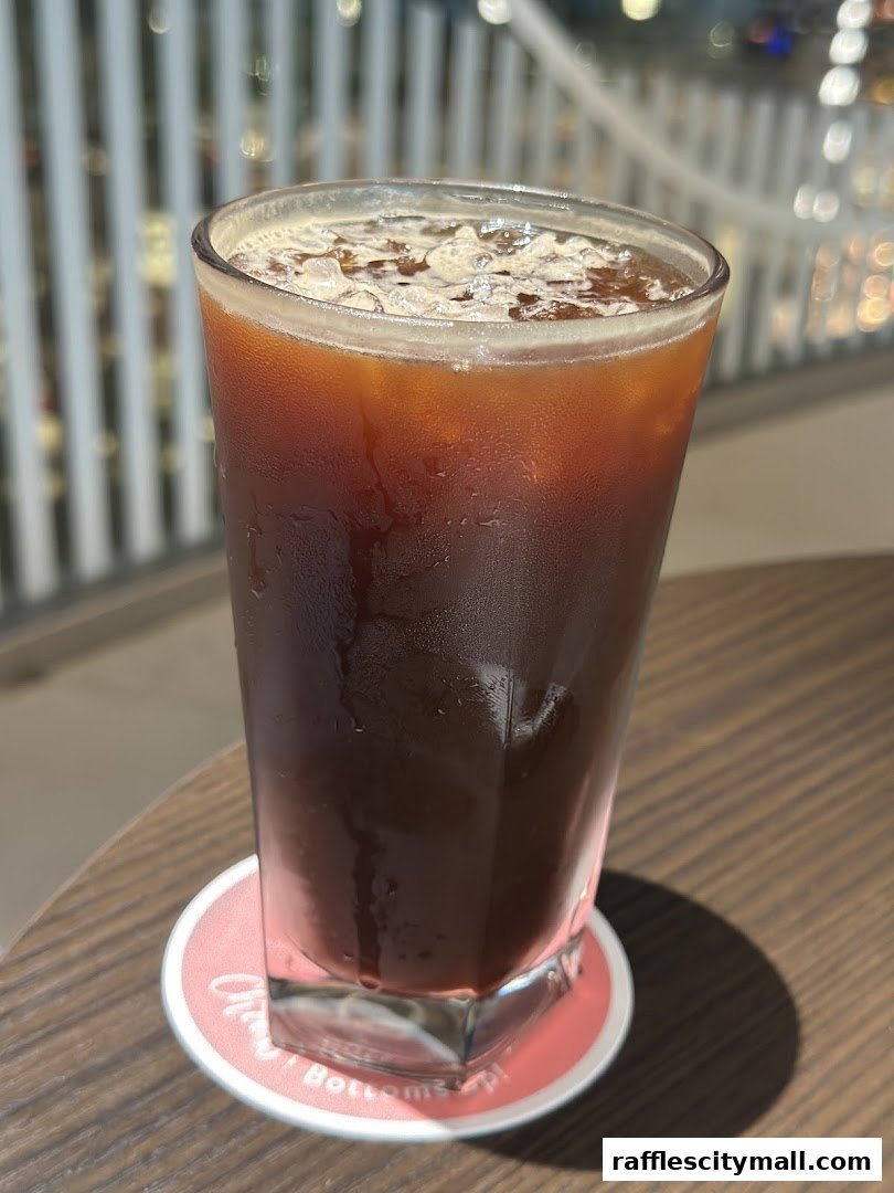 A tall glass of iced coffee with condensation, placed on a coaster.