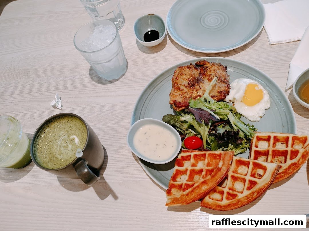 A delicious meal featuring chicken, waffles, a fried egg, salad, and a matcha latte.
