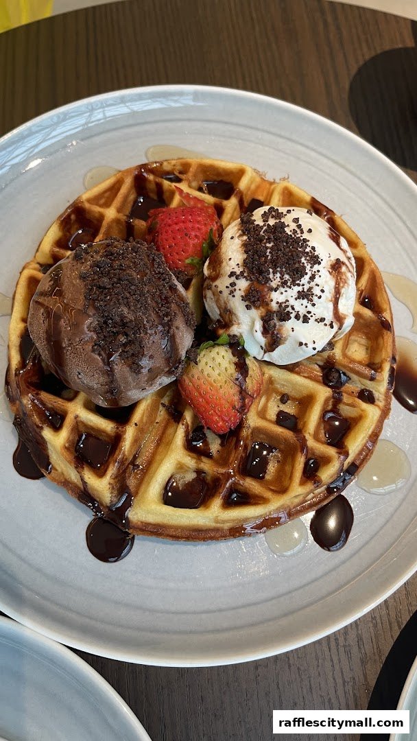 A delicious waffle topped with ice cream, strawberries, and chocolate syrup.