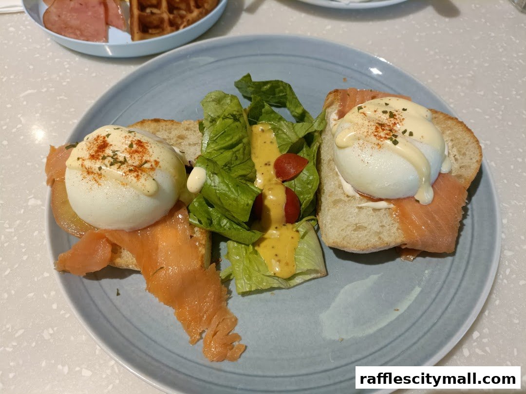 A plate of salmon eggs benedict with a side salad and a waffle in the background.