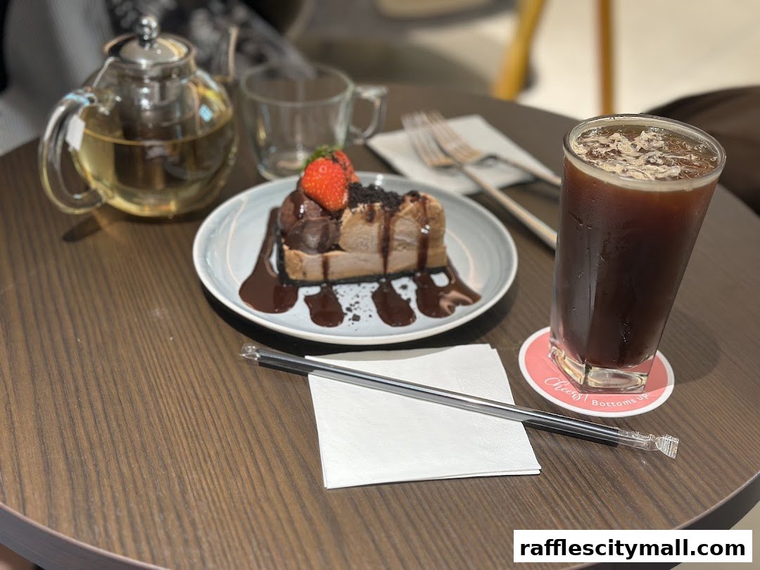 A slice of chocolate cake with strawberries and a glass of iced coffee on a table.