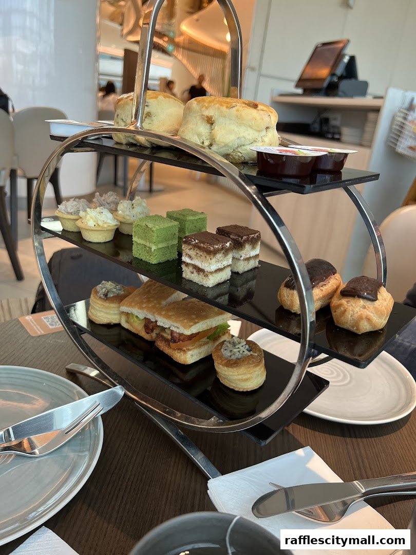 A tiered stand displays a selection of pastries, sandwiches, and scones, set for afternoon tea.