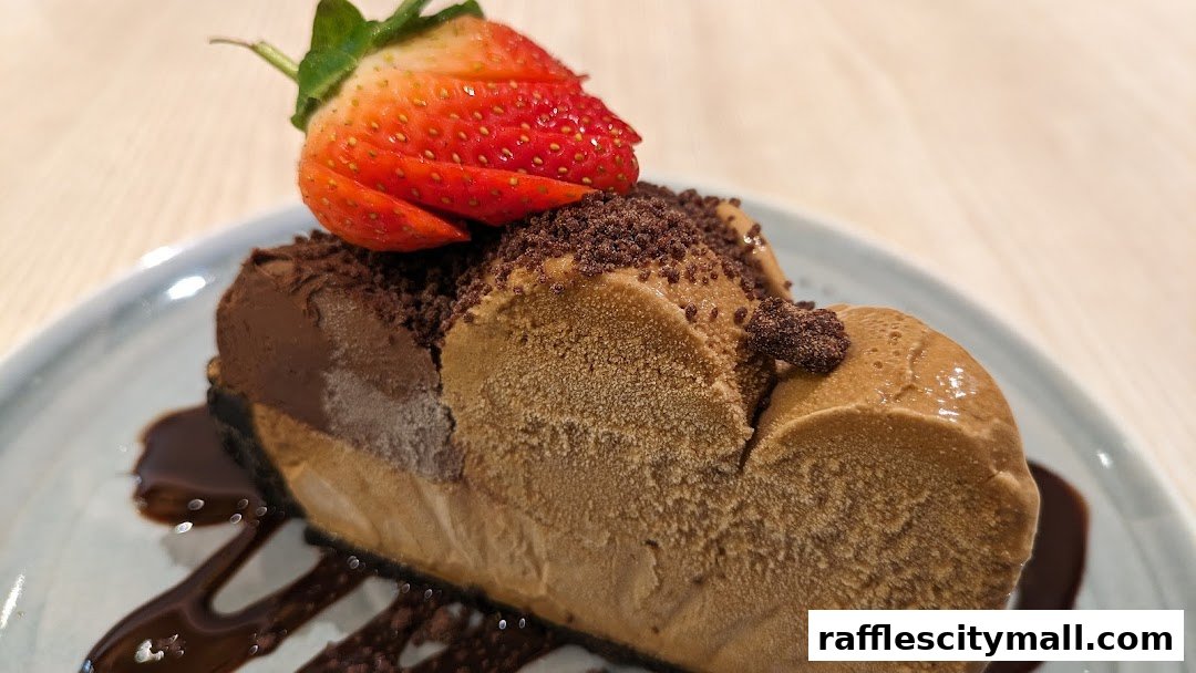 A slice of coffee-flavored dessert topped with chocolate crumbs and a fresh strawberry.