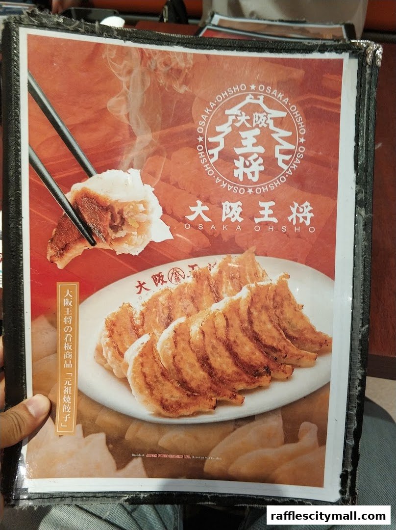 A menu from Osaka Ohsho featuring a close-up of golden-brown gyoza being picked up by chopsticks.