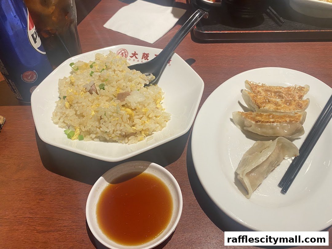 A plate of fried rice and pan-fried dumplings with a dipping sauce and a drink.