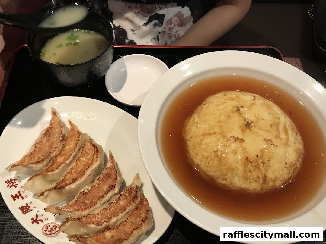 A plate of pan-fried gyoza, a bowl of miso soup, and a large omelet dish.