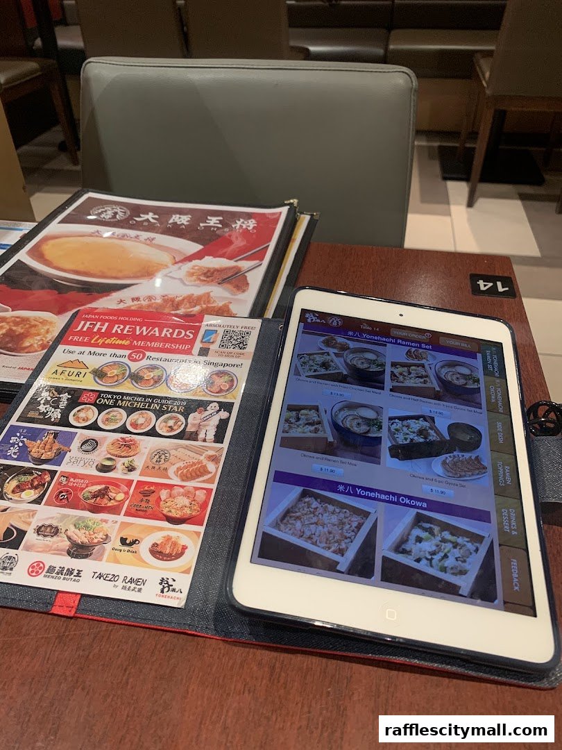 A table at Osaka Ohsho with a digital menu on a tablet and a physical menu.