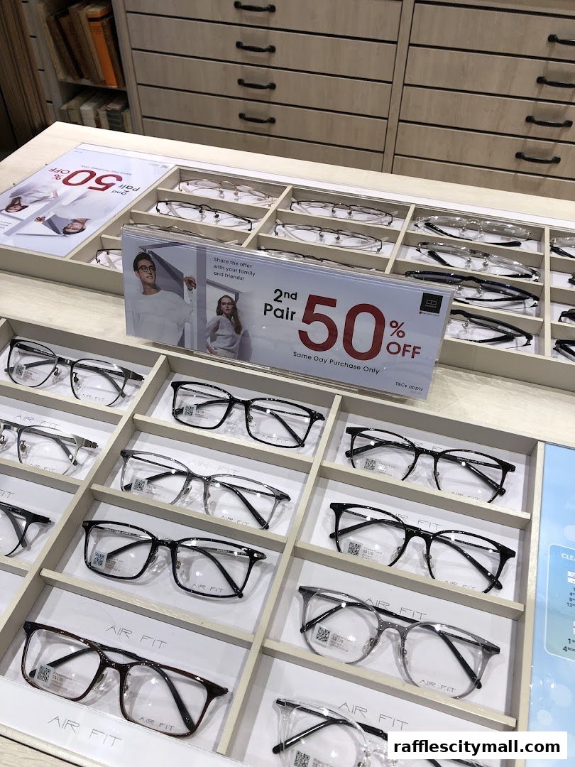 A display of various eyeglasses with a promotional sign for 50% off a second pair.