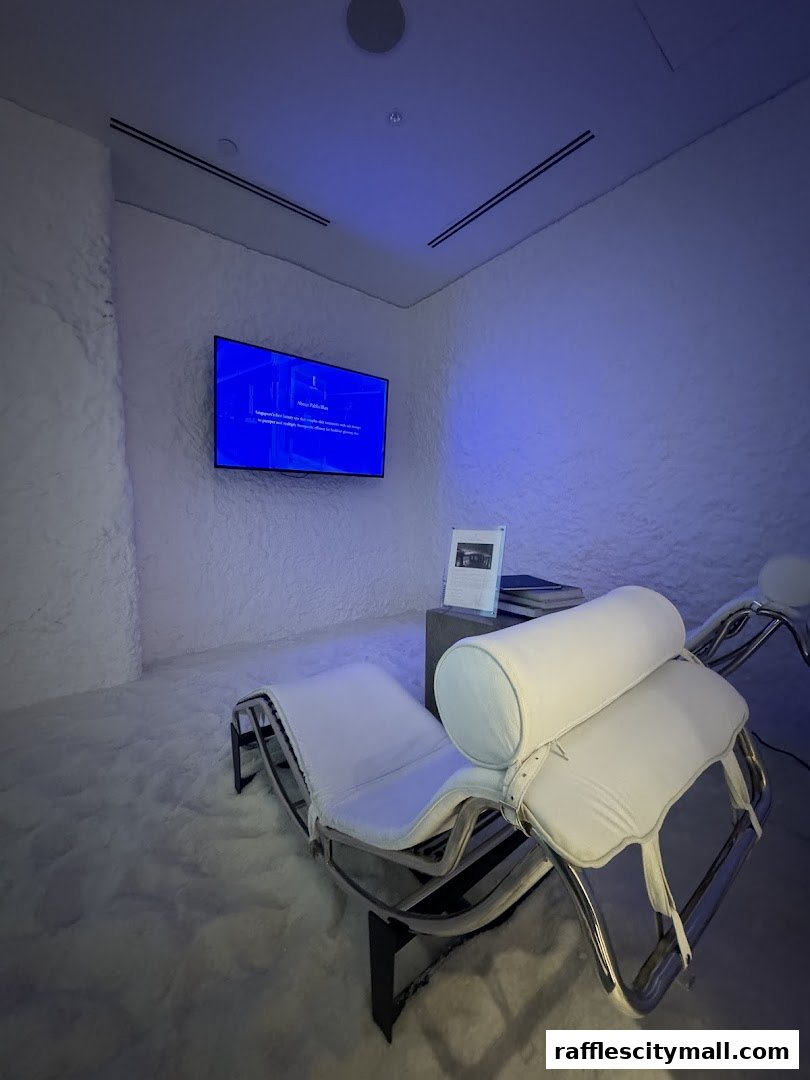 A serene room with salt-covered walls, floor, and lounge chairs, featuring a screen on the wall.