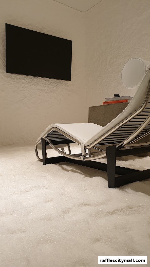 A modern lounge area with a chaise lounge, TV, and a floor covered in white crystals.