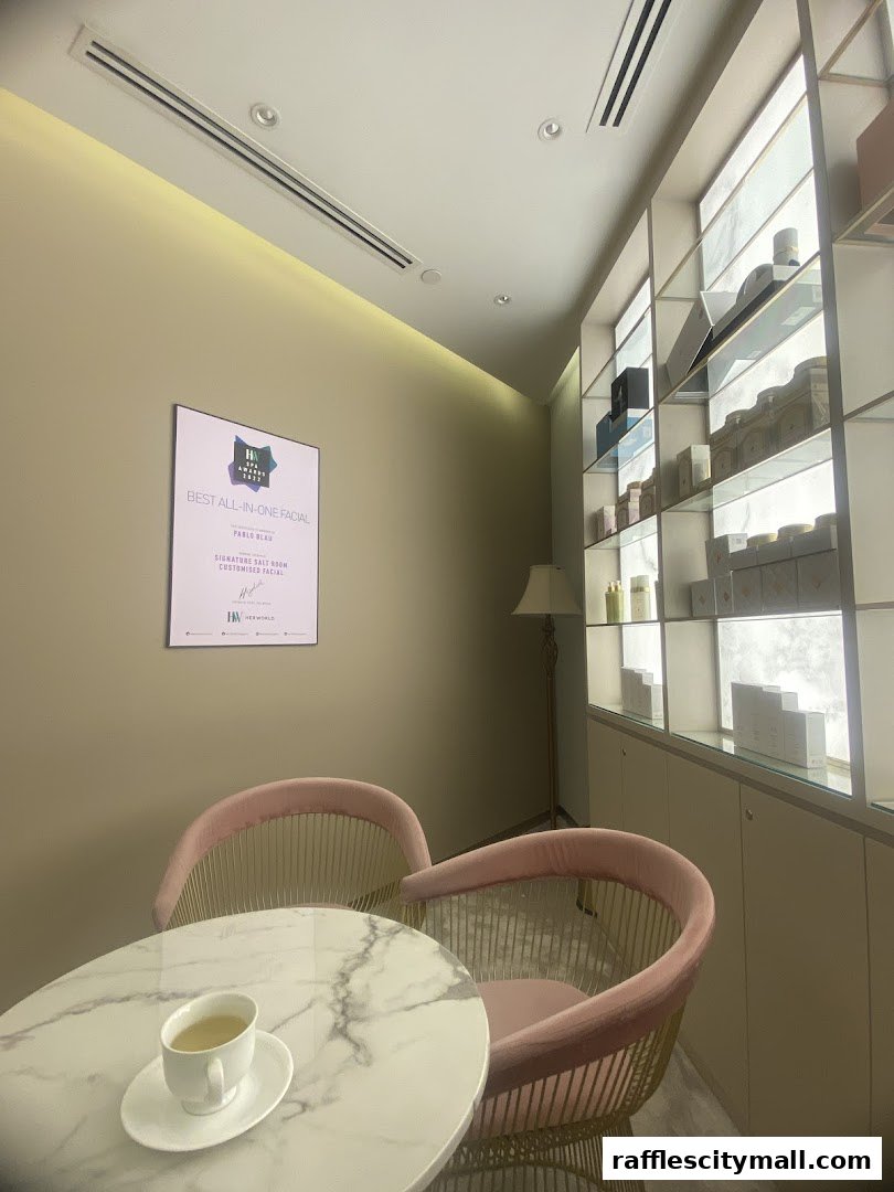 A waiting area with a marble table, pink chairs, and shelves displaying products.