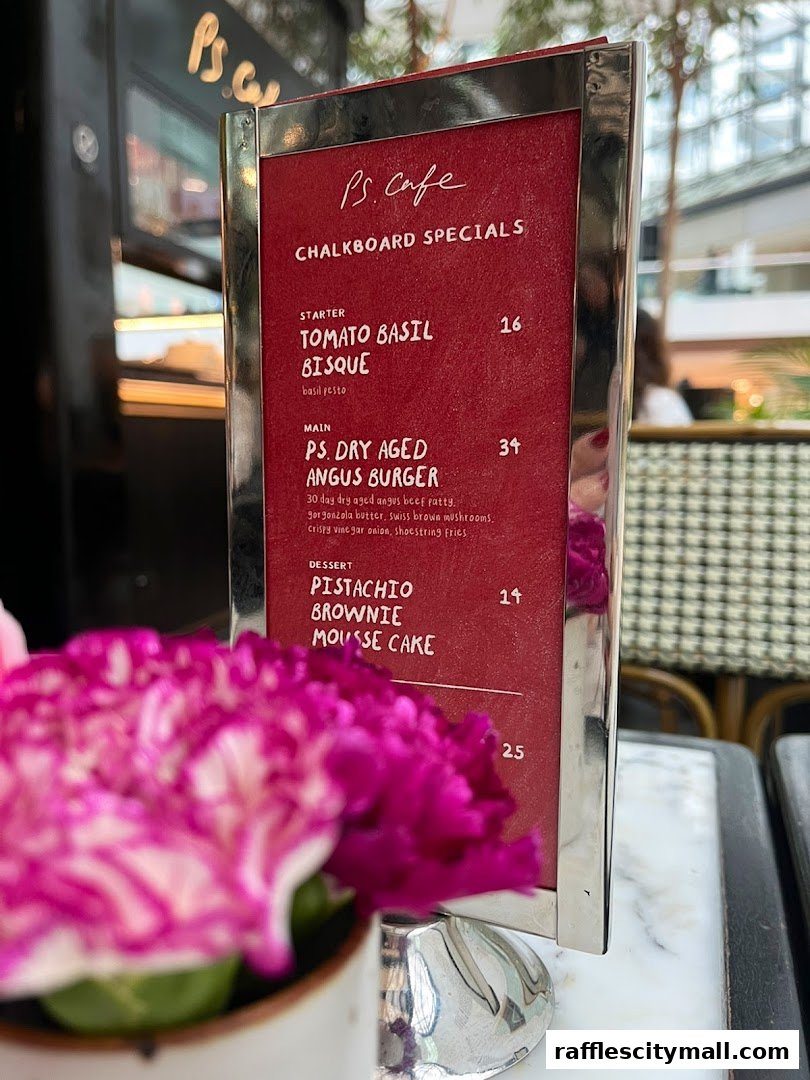 A menu board from PS.Cafe featuring specials like Tomato Basil Bisque and Angus Burger.