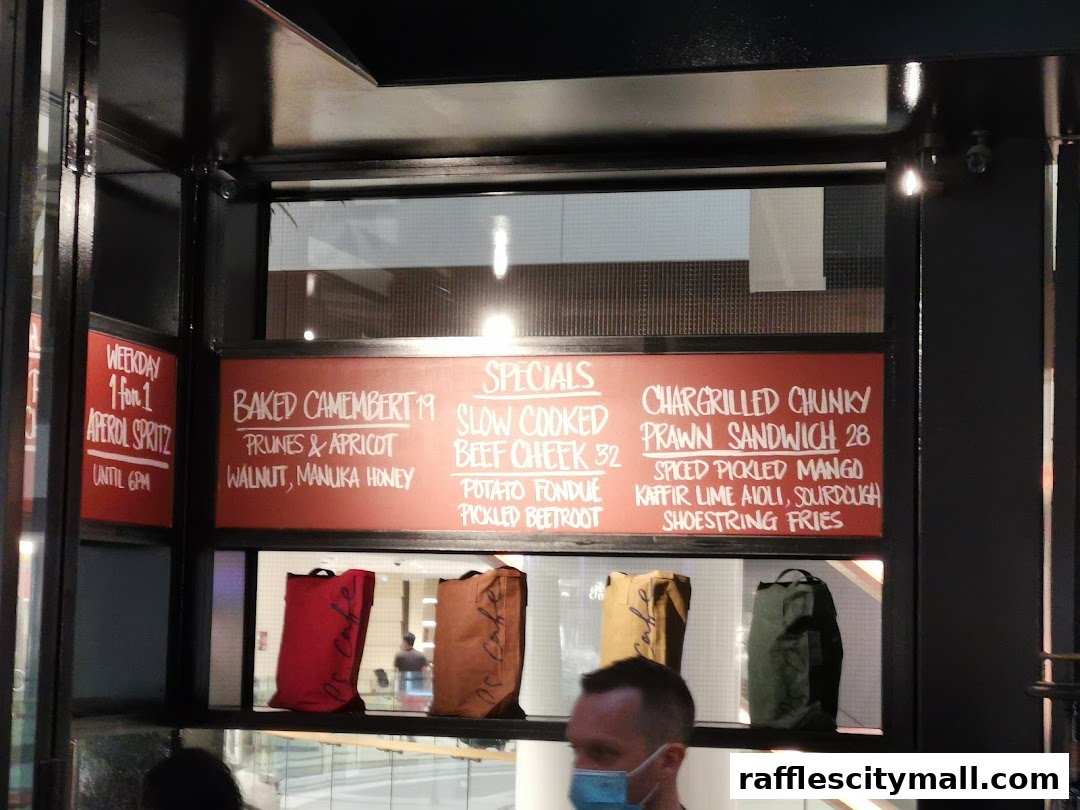A menu board displays specials including baked camembert, slow-cooked beef cheek, and prawn sandwiches.