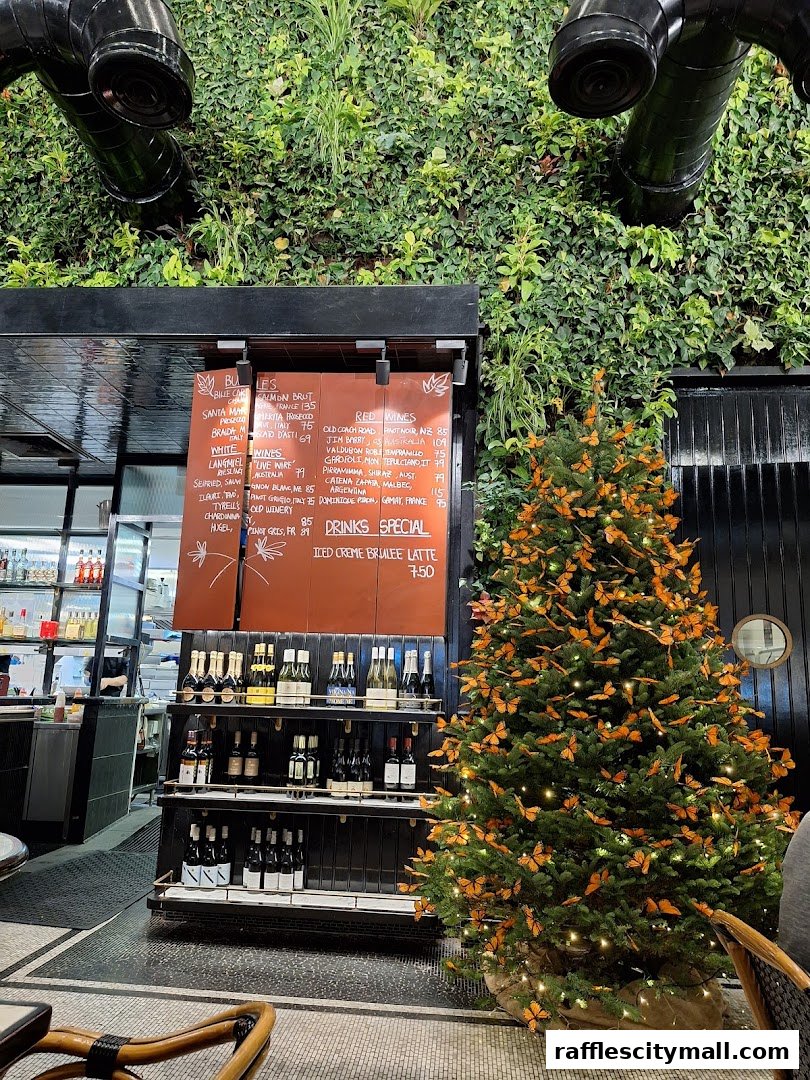 A festive Christmas tree adorned with monarch butterflies inside a cafe with a living wall.
