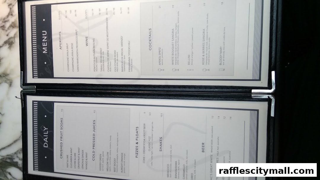 A menu from PS.Cafe Raffles City, featuring drinks like sodas, juices, cocktails, and beers.