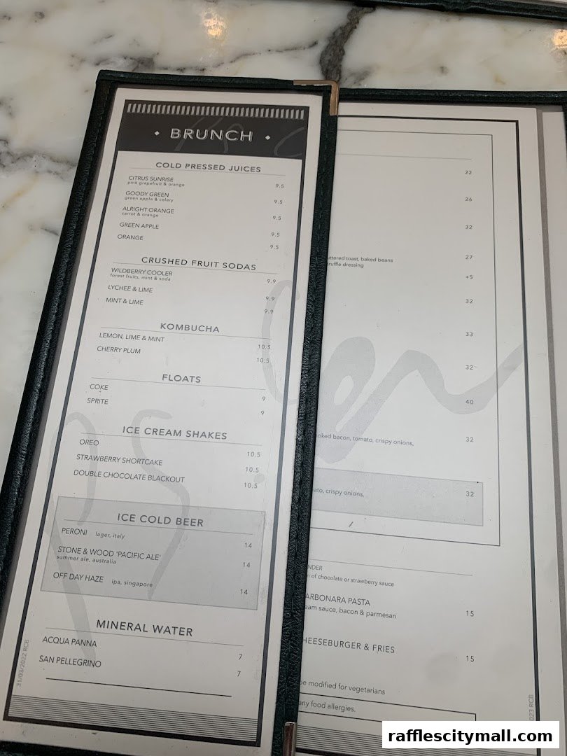 A menu from PS.Cafe Raffles City featuring brunch items, juices, sodas, shakes, beer, and water.