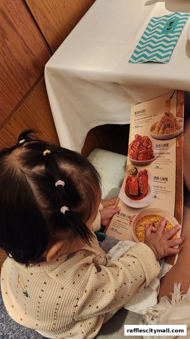 A child looks at a menu featuring various crab dishes and other food items.