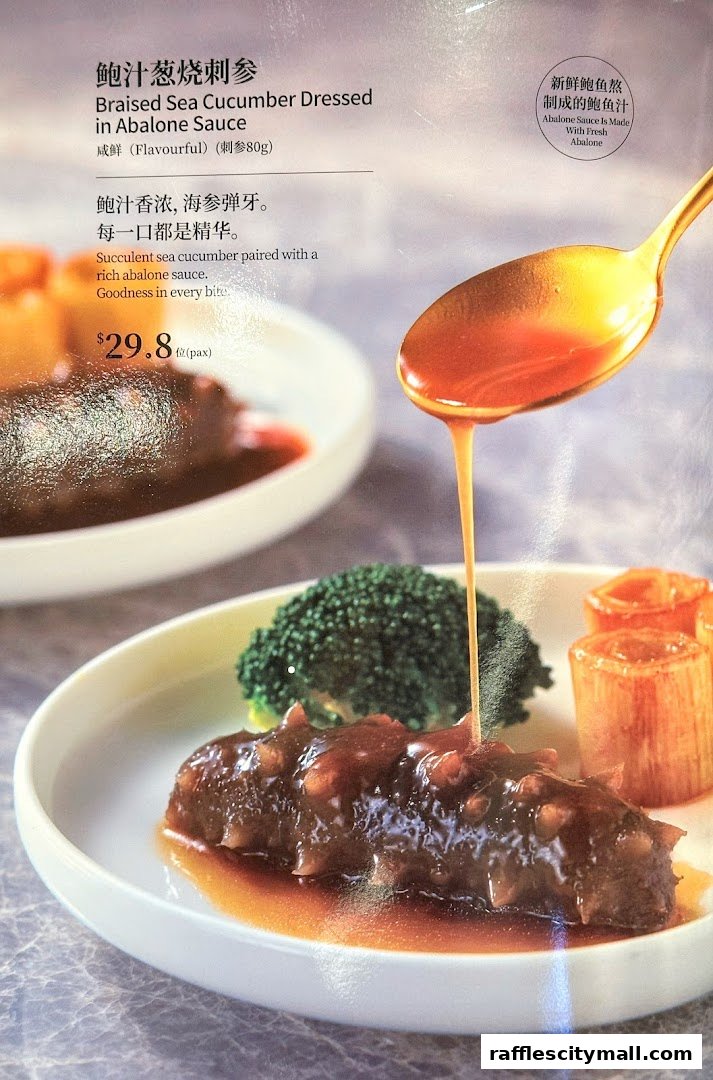 A close-up of a Braised Sea Cucumber dish with broccoli and leeks, drizzled with abalone sauce.