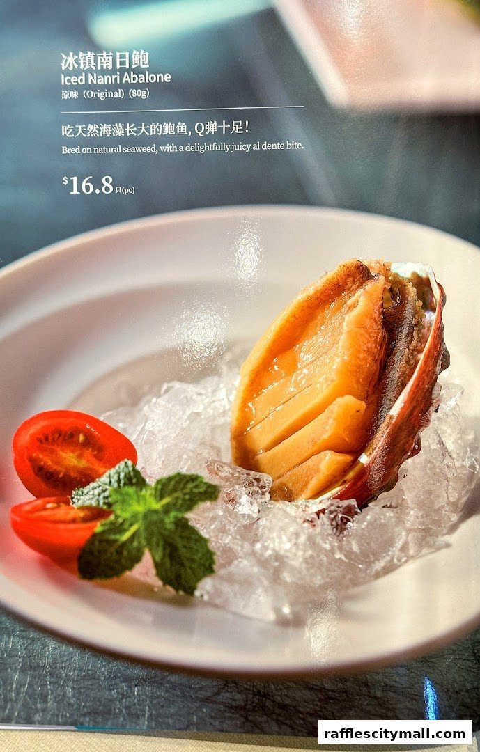 A close-up of Iced Nanri Abalone served on ice with cherry tomatoes and mint.