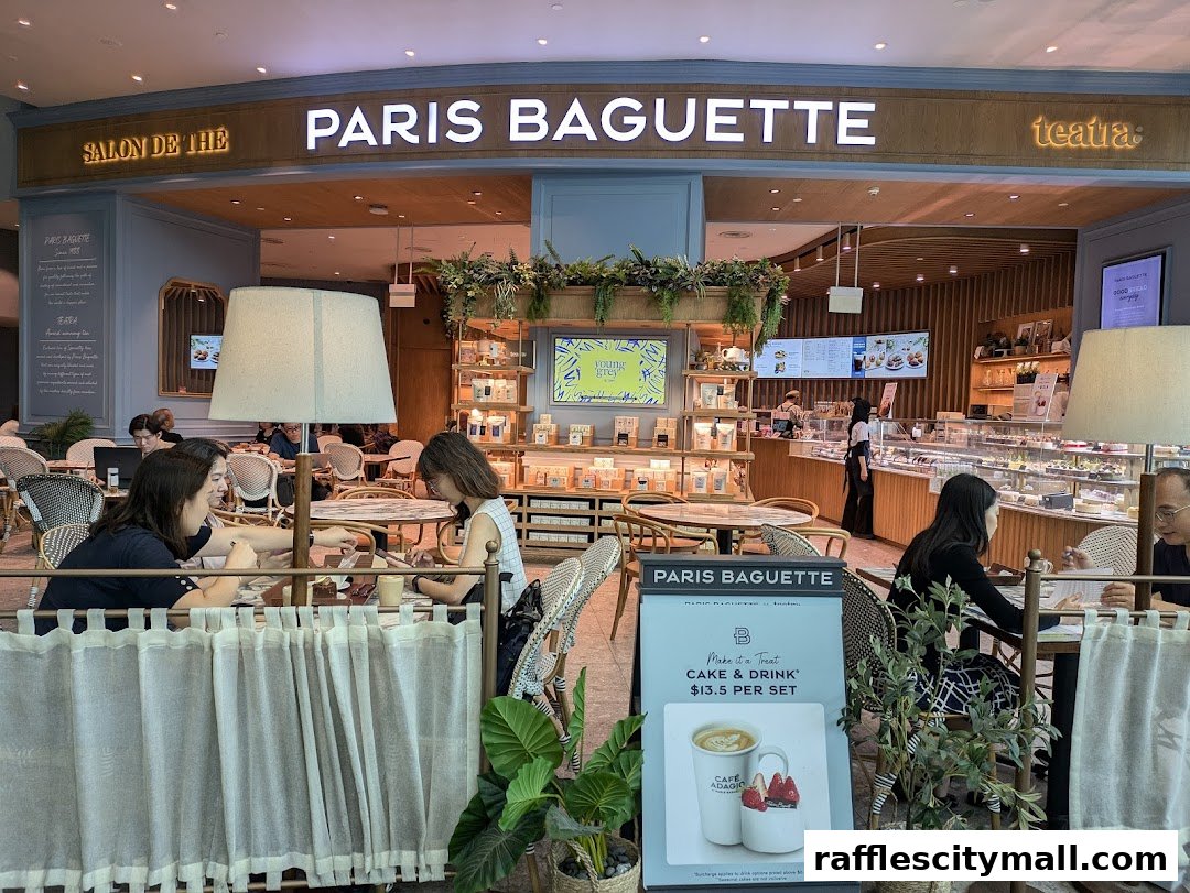 Interior view of Paris Baguette cafe with customers seated at tables and display cases of pastries.