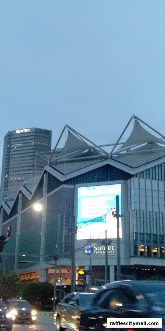 A view of the Suntec City complex with cars on the road in the foreground.