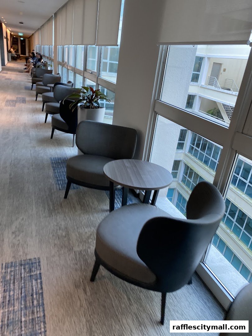 A waiting area with comfortable chairs and small tables next to large windows.