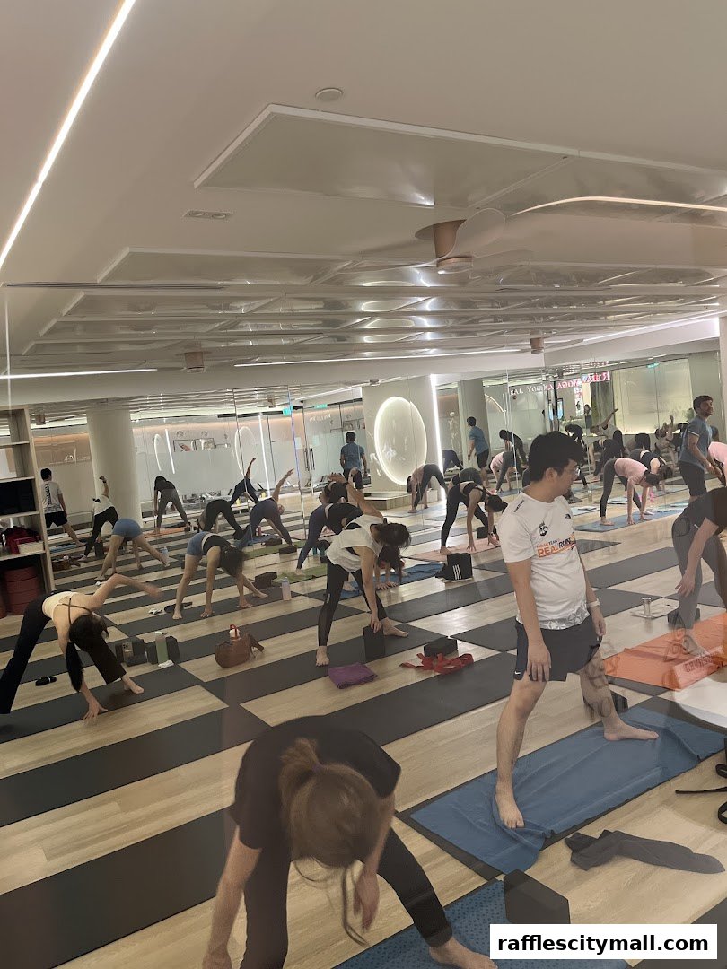 People practicing yoga in a bright studio with mirrors and modern lighting.