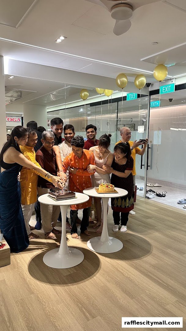 A group of people celebrating with cakes and balloons inside a yoga studio.