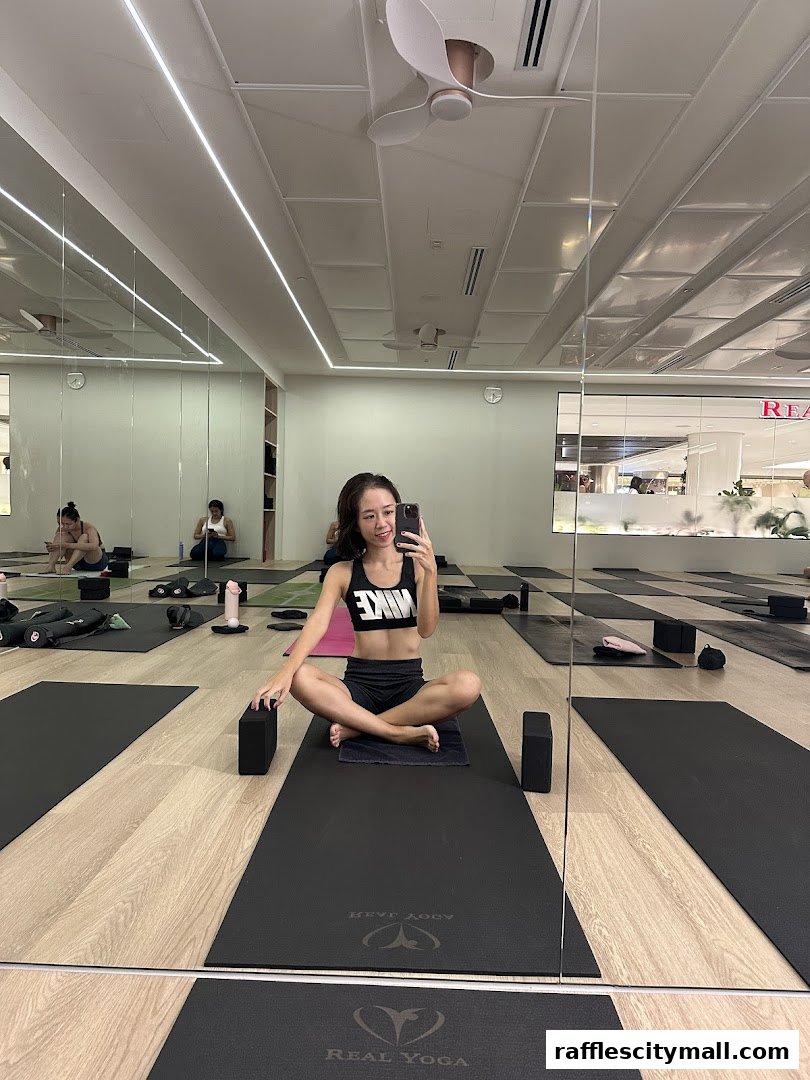 A woman takes a selfie in a yoga studio with mats and blocks laid out.