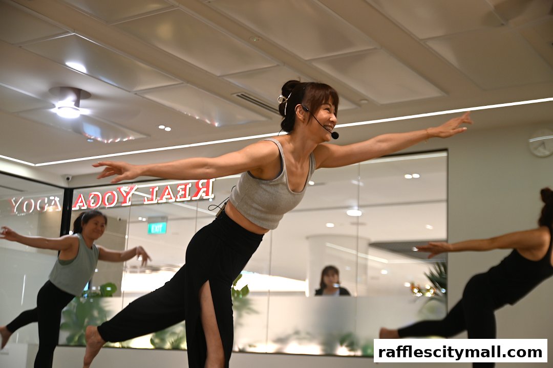 A yoga instructor leads a class with students practicing poses in a bright studio.