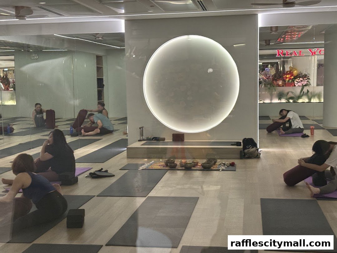 People practicing yoga in a studio with mirrors and a large circular light.