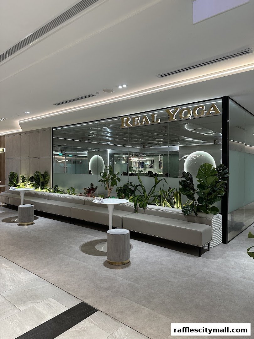 The entrance of Real Yoga Premium at Raffles City, featuring a modern design with plants and seating.