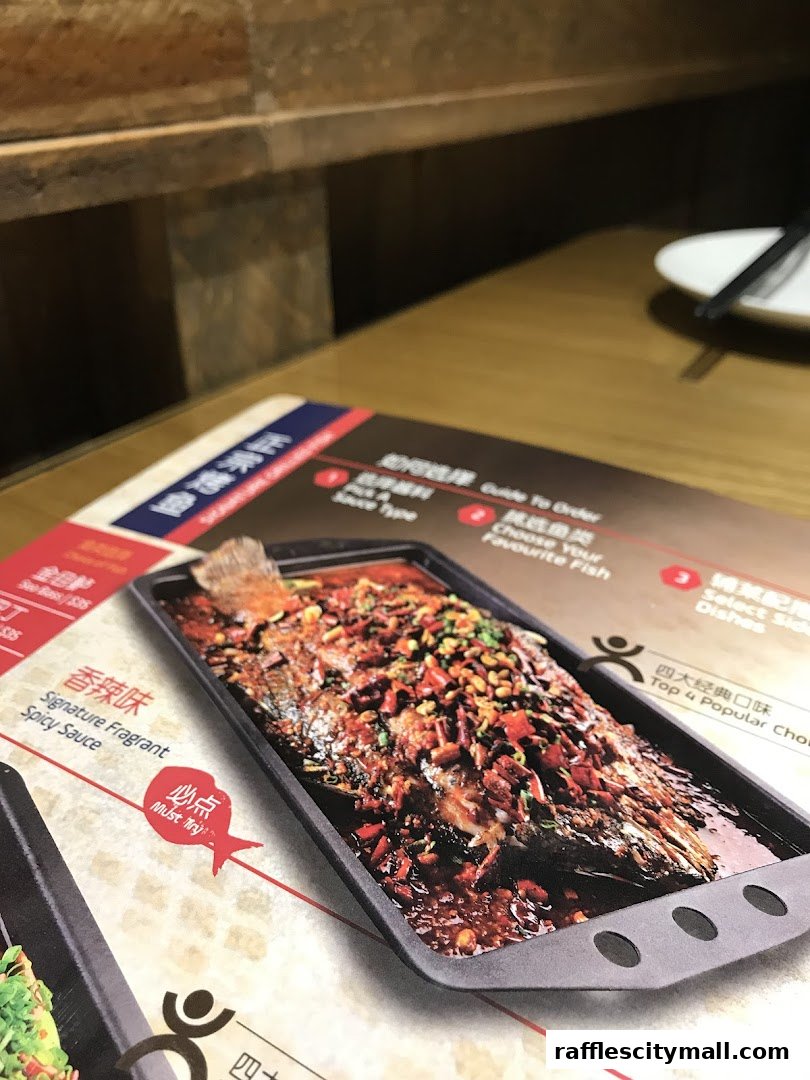 A close-up of a menu featuring a spicy fragrant fish dish with accompanying text.