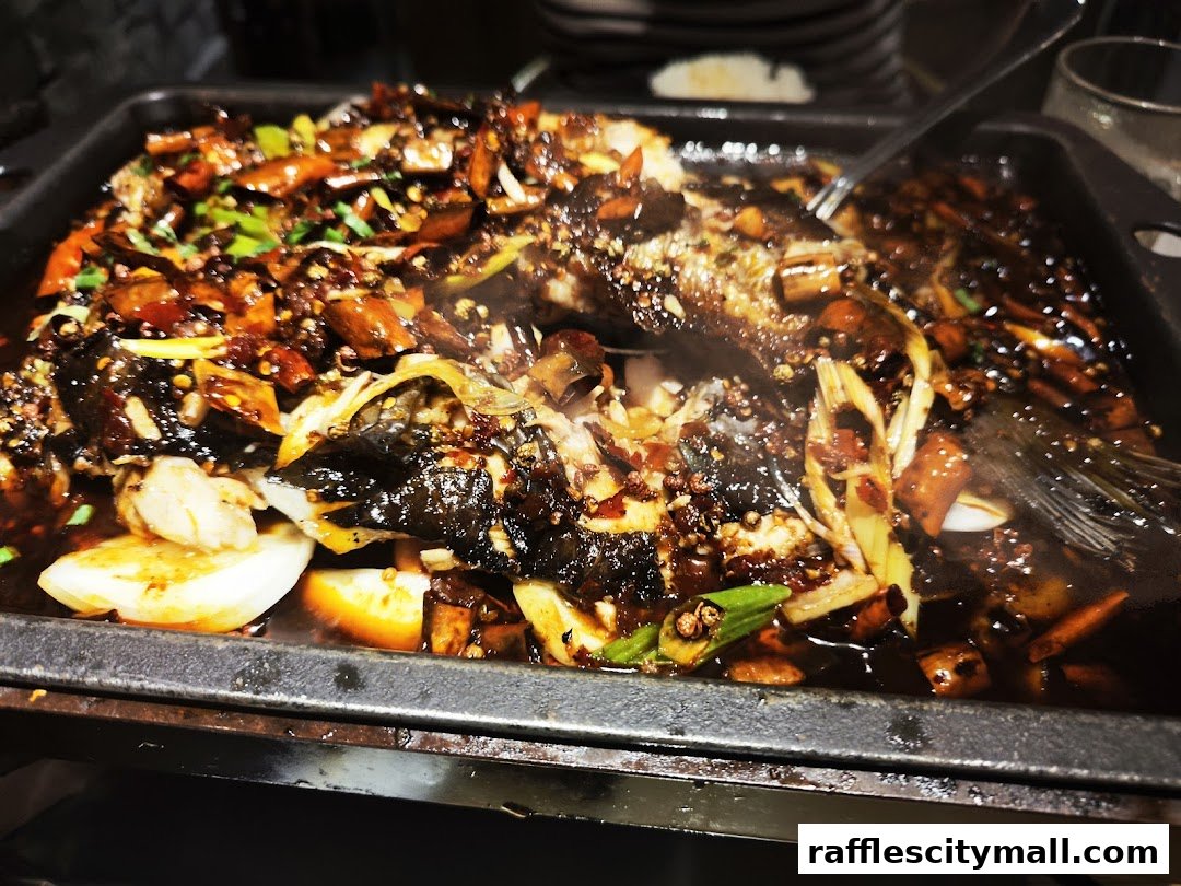 A close-up of a steaming claypot dish with fish, vegetables, and spices.