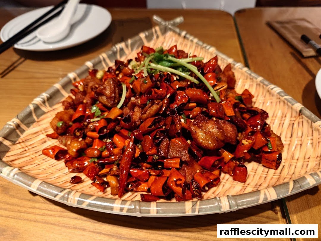 A close-up of a spicy Sichuan dish with fried chicken and dried chilies.