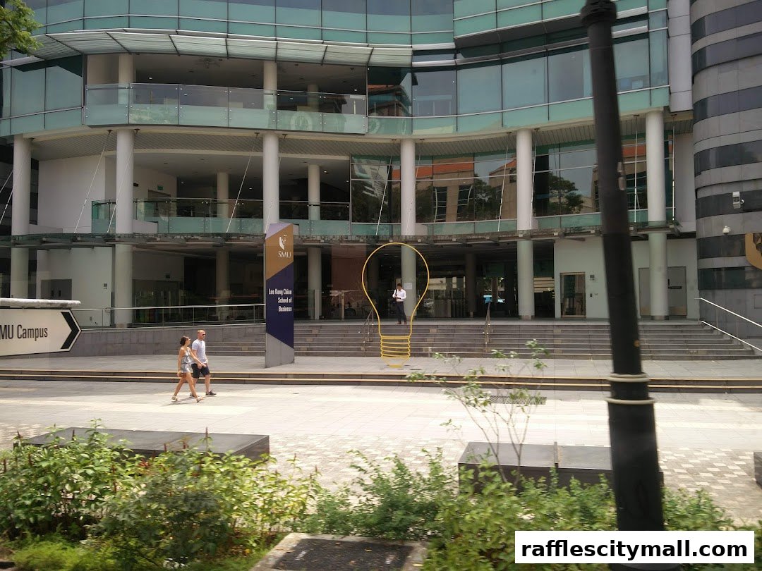 A modern building with glass facade and a large lightbulb sculpture outside.