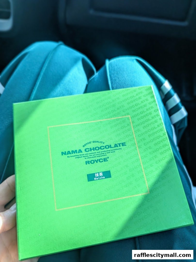 A person holds a green box of Royce Nama Chocolate, Matcha flavor.