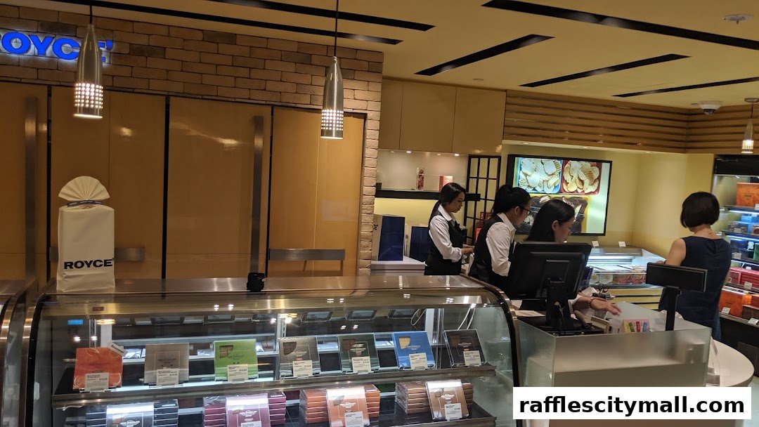 Staff serving customers at the counter of a Royce chocolate shop with display cases.