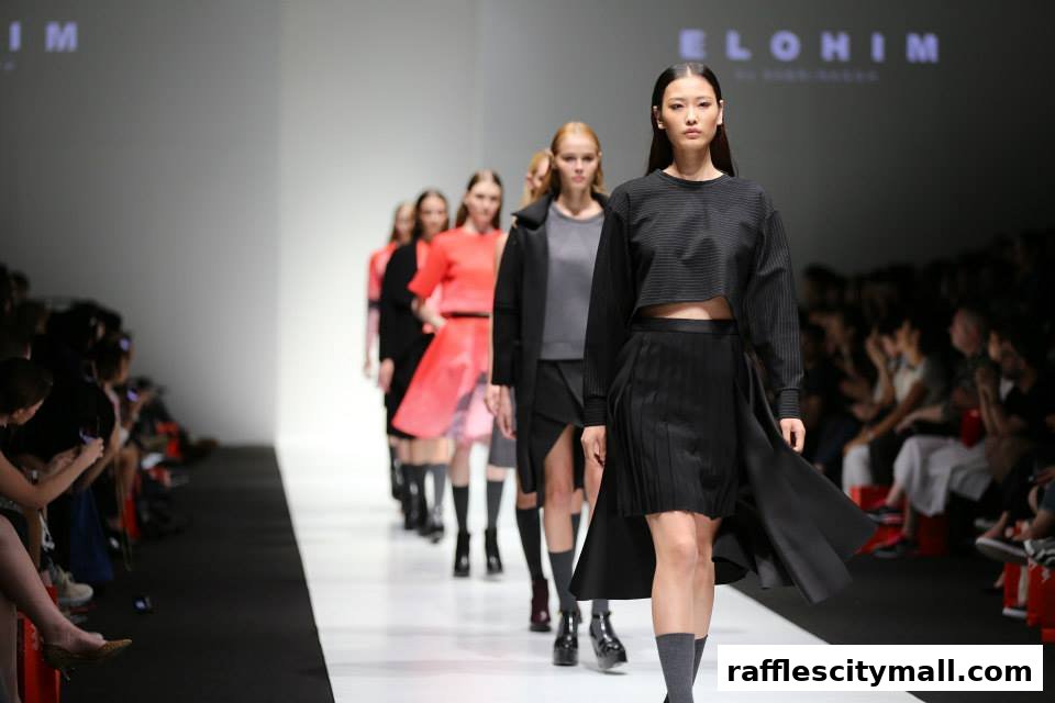 Models walk down a runway showcasing fashion designs, with an audience watching.