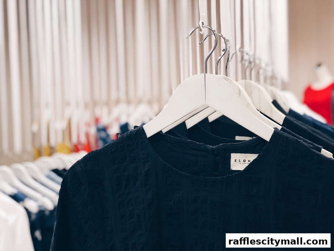 Close-up of a black textured top on a hanger, with other clothing items in the background.