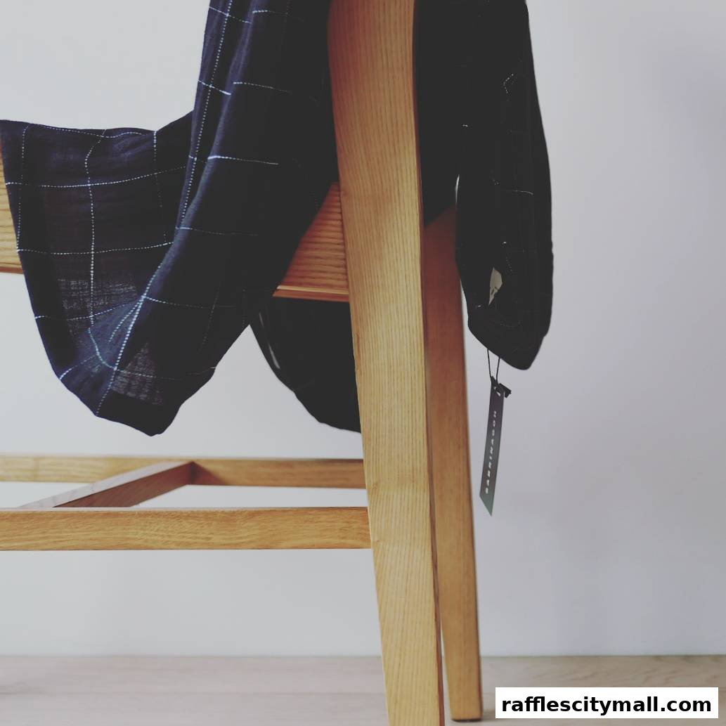 A dark, checkered garment draped over a wooden chair with a tag.