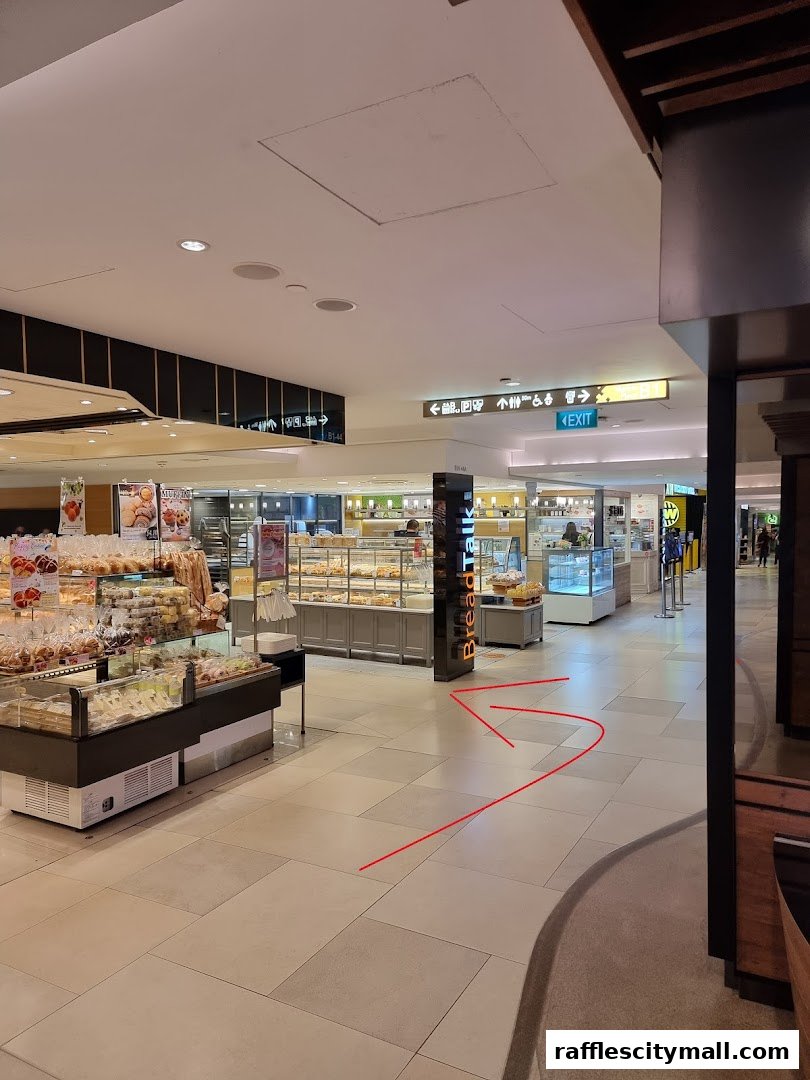 A view of a bakery shop with displays of bread and pastries, and directional signs.
