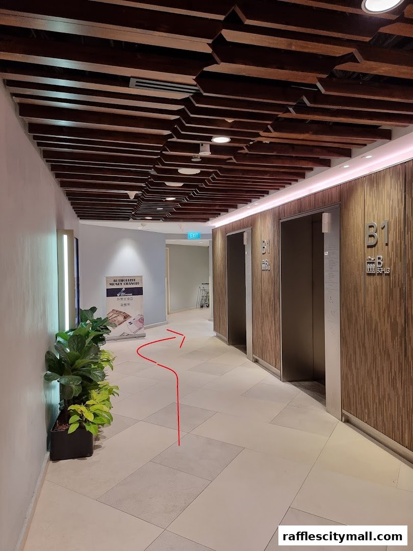 A hallway with elevators and a sign for a money changer, with a red arrow indicating a path.