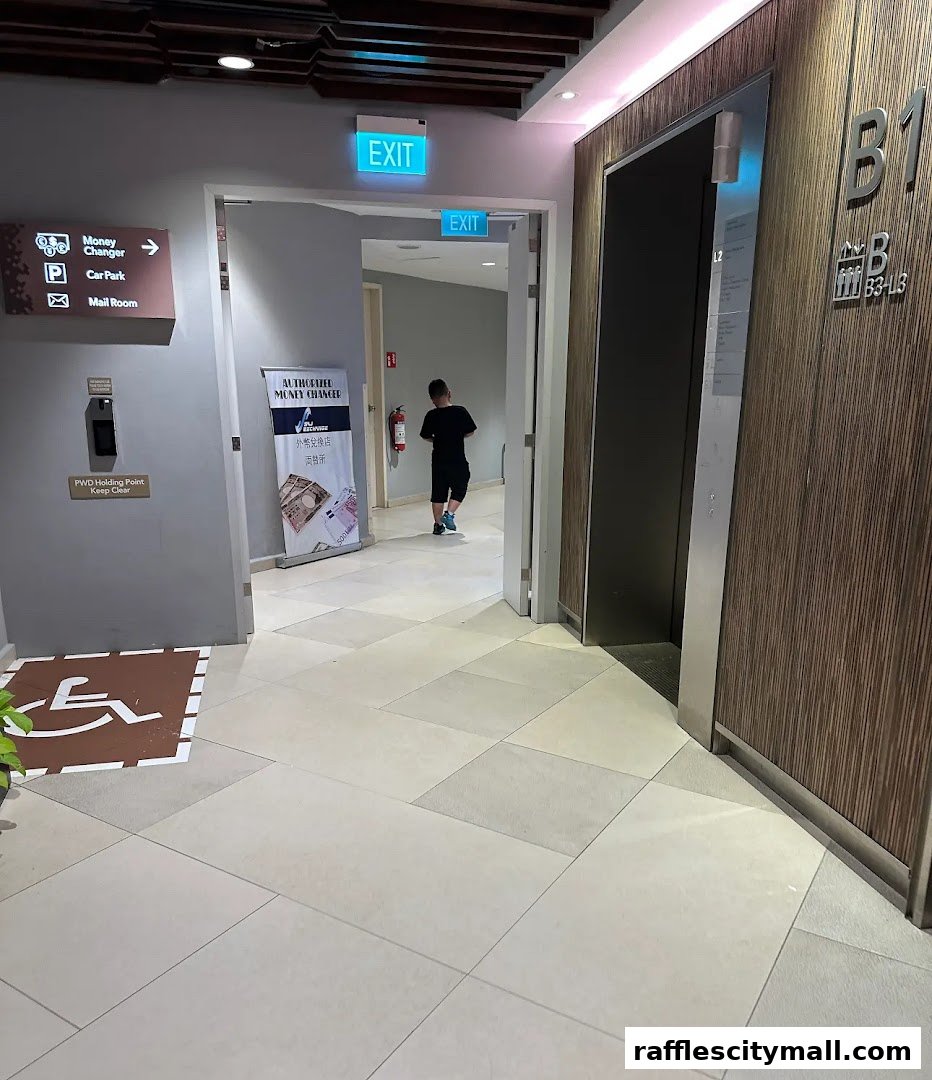 An interior view of a mall hallway with signs for a money changer and an elevator.