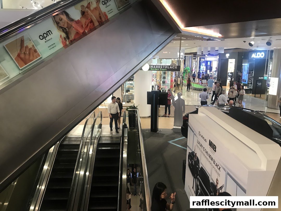 Interior view of a shopping mall with escalators, shops, and a car display.