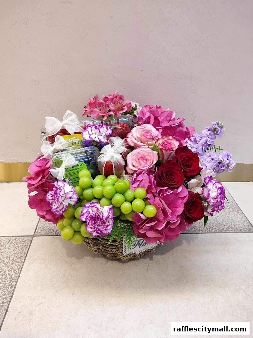 A beautifully arranged fruit and flower basket with grapes, strawberries, roses, and carnations.