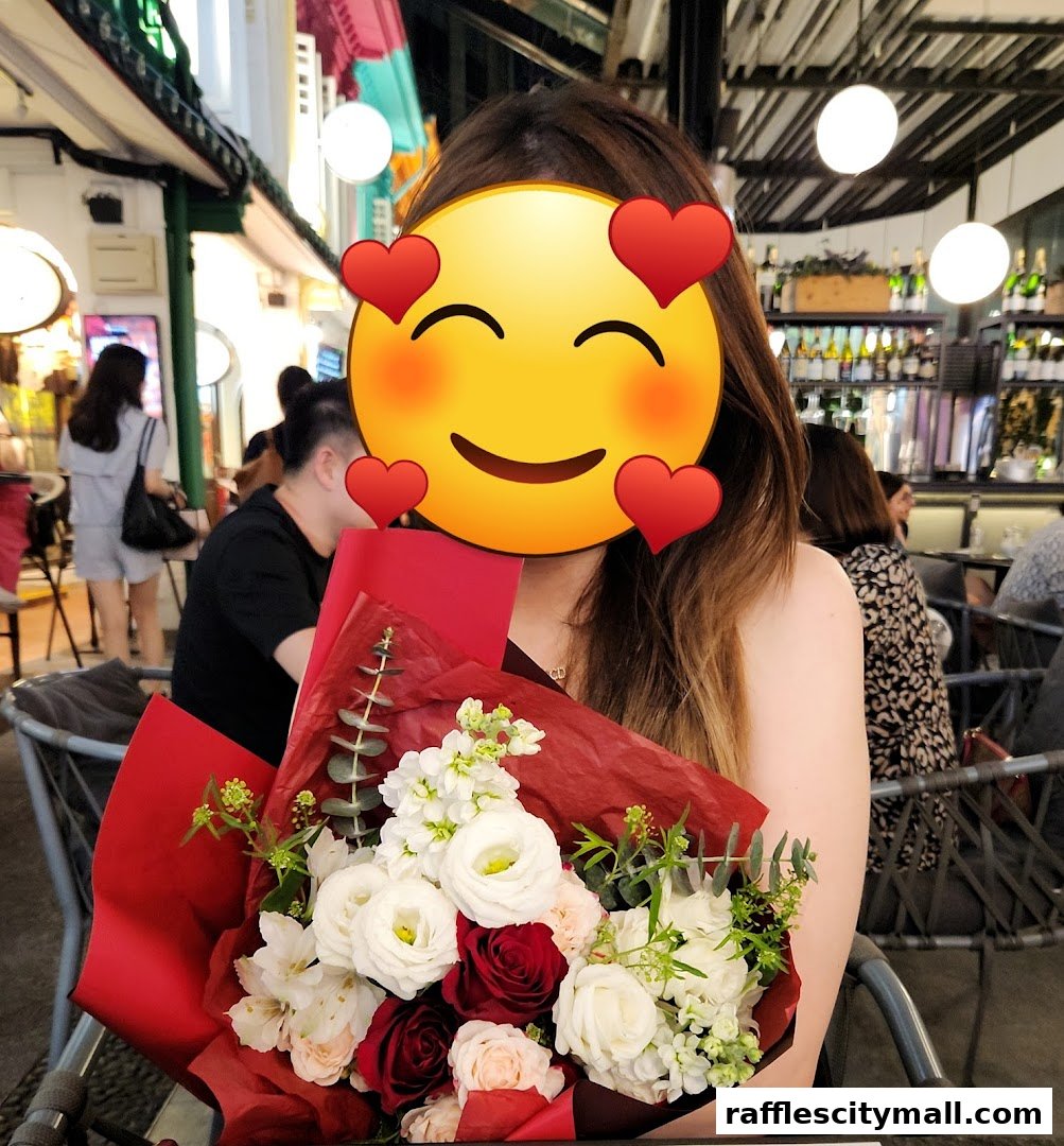 A person holds a beautiful bouquet of red and white flowers in front of a restaurant.