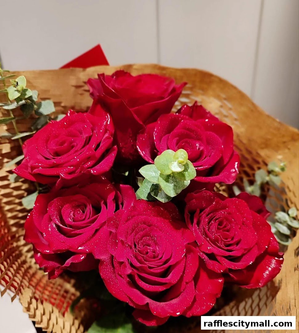 A close-up of a bouquet of deep red roses with water droplets, wrapped in brown paper.